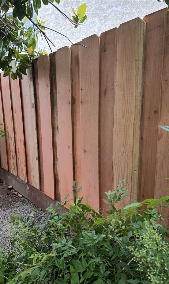 Dark stained board-on-board wood fence with a cap rail
