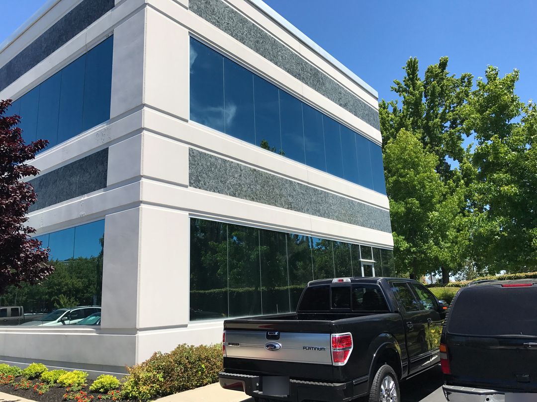 Multi-story commercial office building with freshly painted white exterior and stone-look panels