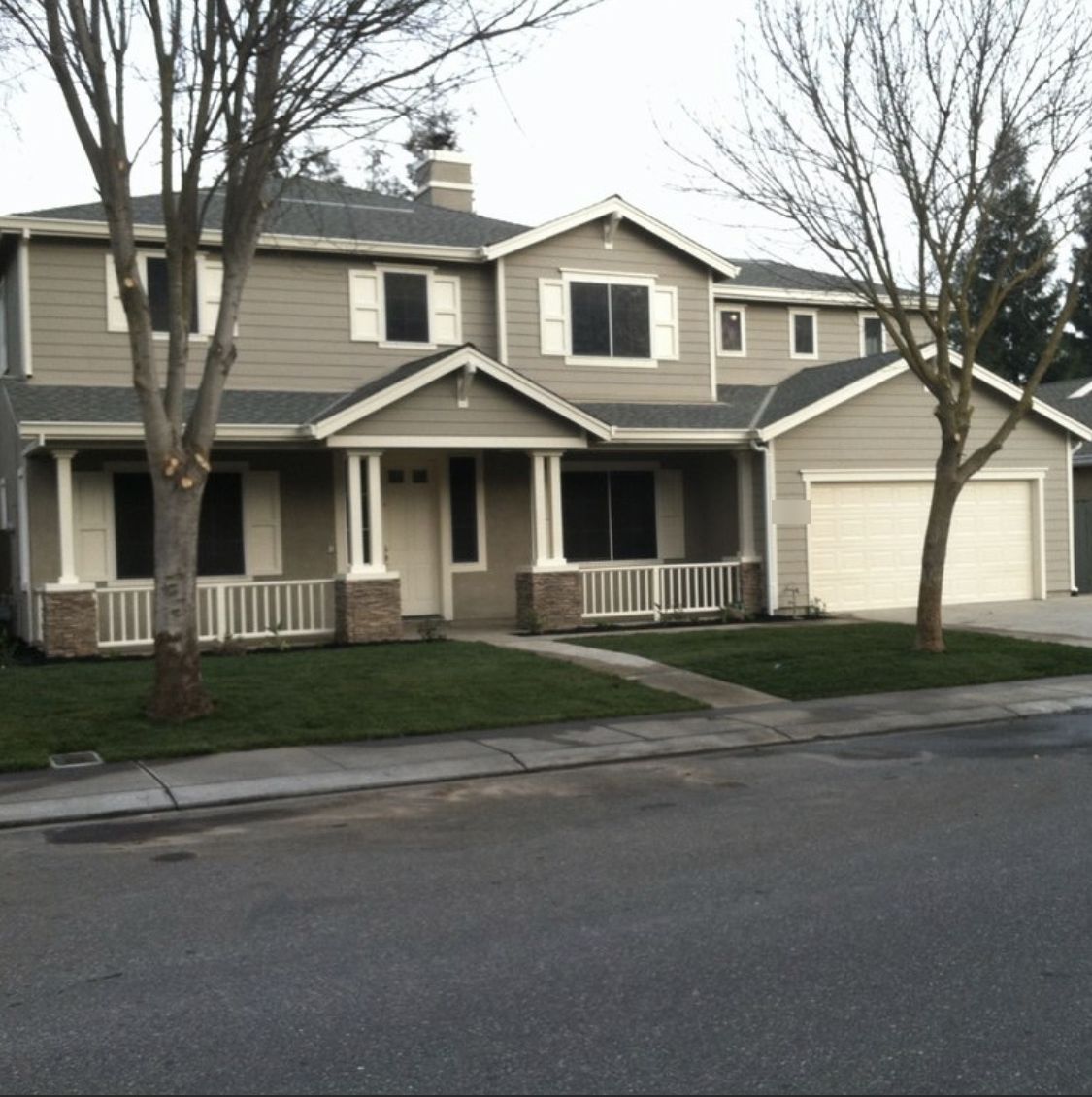 Two-story craftsman home with gray siding, white trim and a covered front porch