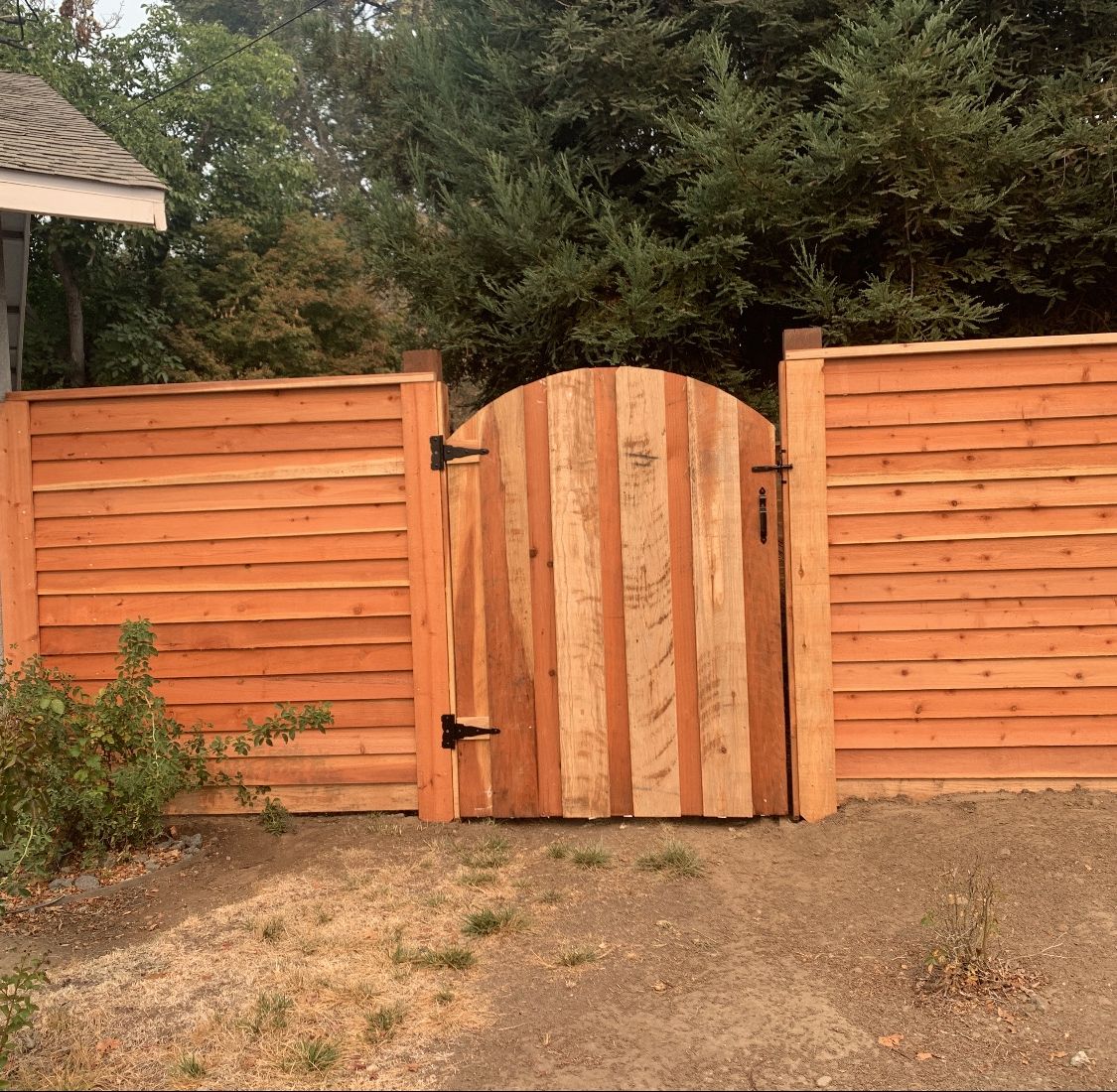 Horizontal board redwood fence with an arched vertical-board gate