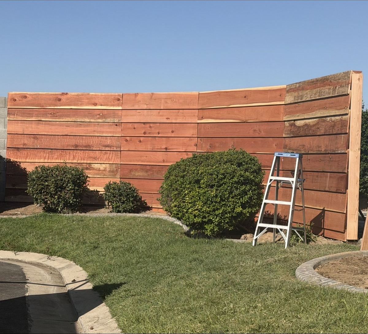 Horizontal redwood board fence during installation by the California Crews team