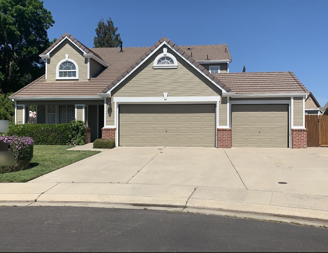 Home exterior painted tan with white trim and matching garage doors