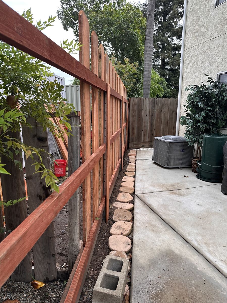 New redwood picket fence with rails going in along a side yard next to the old fence