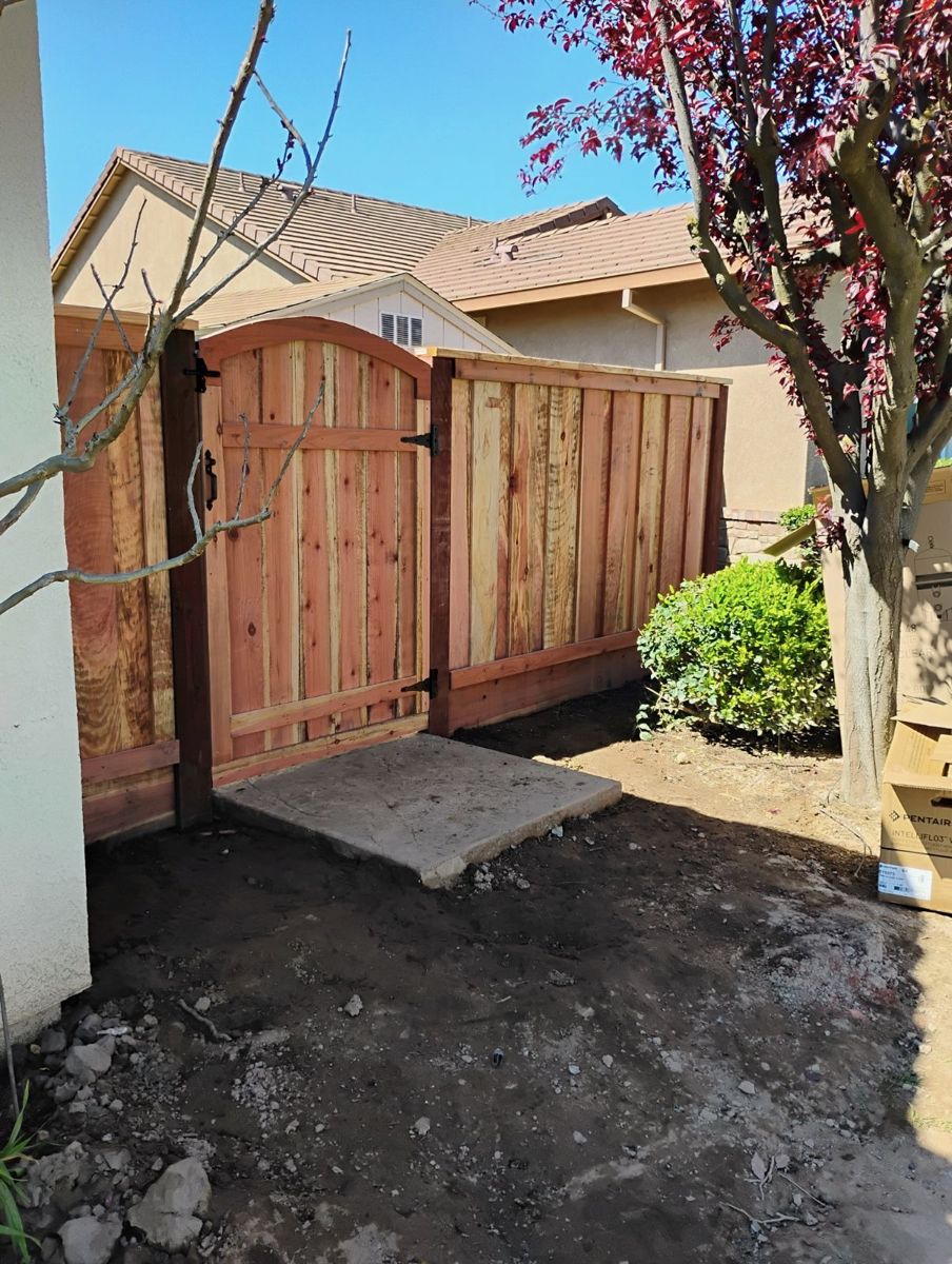New redwood fence with an arched gate just installed in a side yard