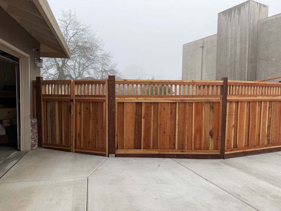 New redwood fence and gate with lattice top along a driveway next to a garage