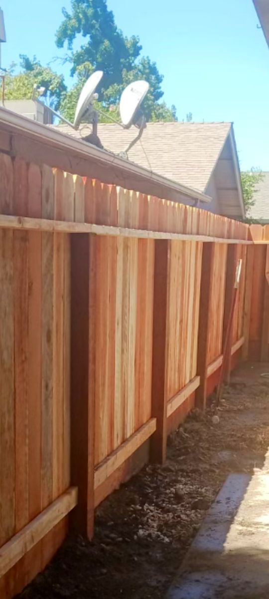 Redwood fence with posts and rails along a side yard