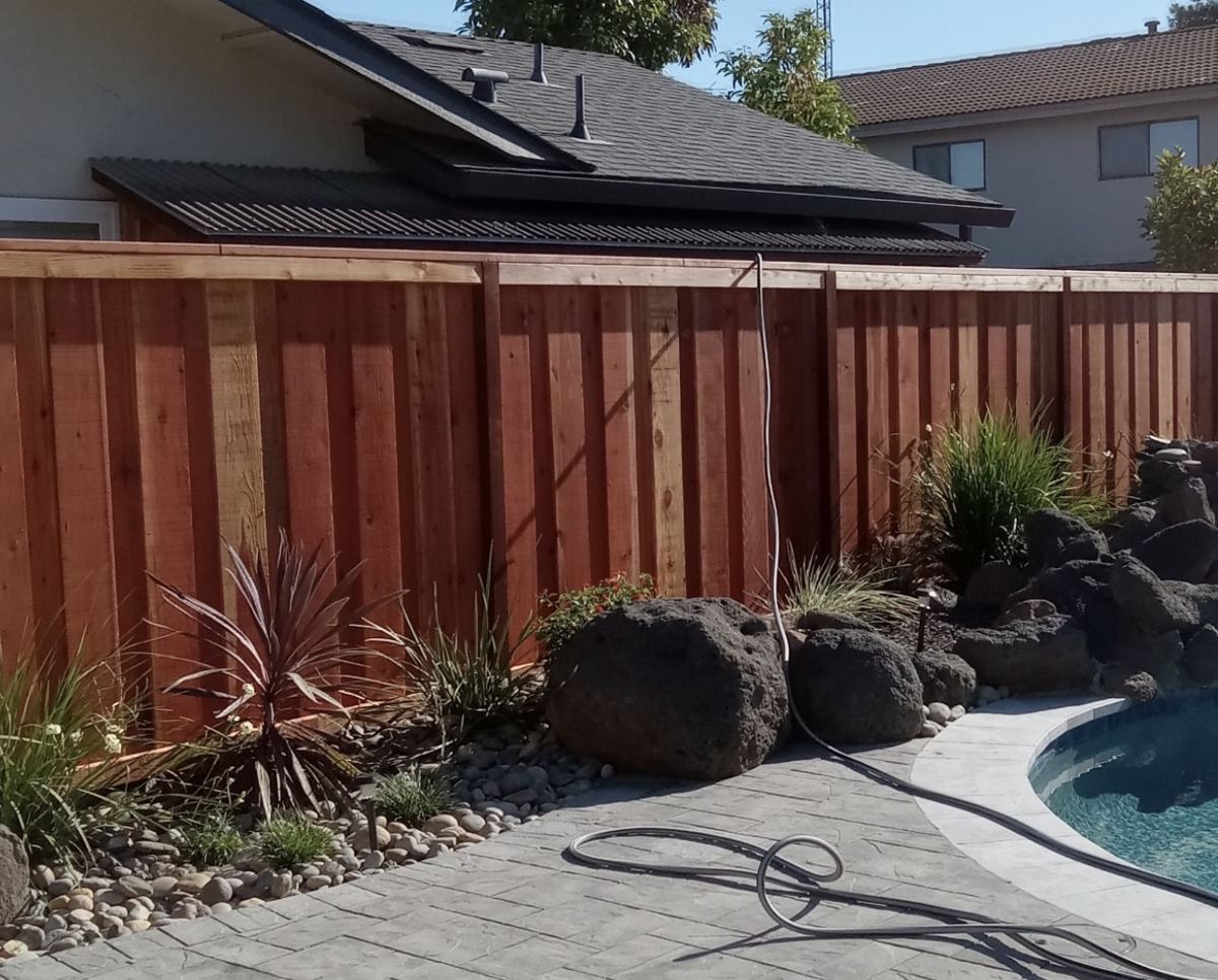 Redwood privacy fence next to a pool with landscaping