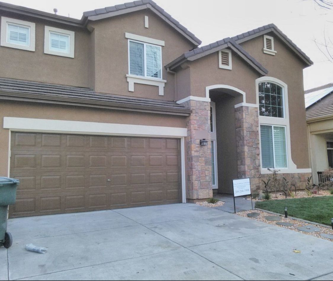 Stucco home painted brown with stone accents and a California Crews sign out front