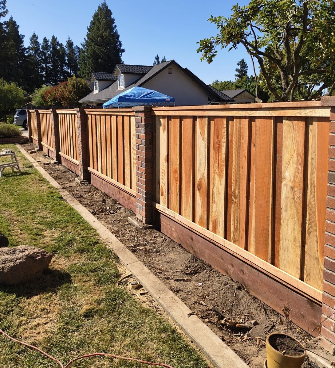 Completed wood fence with brick pillar posts and concrete base